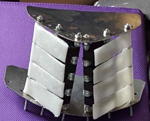 Twee metalen profielen met draadeinden er tussen geschroefd. Op de draadeinden zijn schakelaars en langwerpige plastic toetsen gemonteerd.